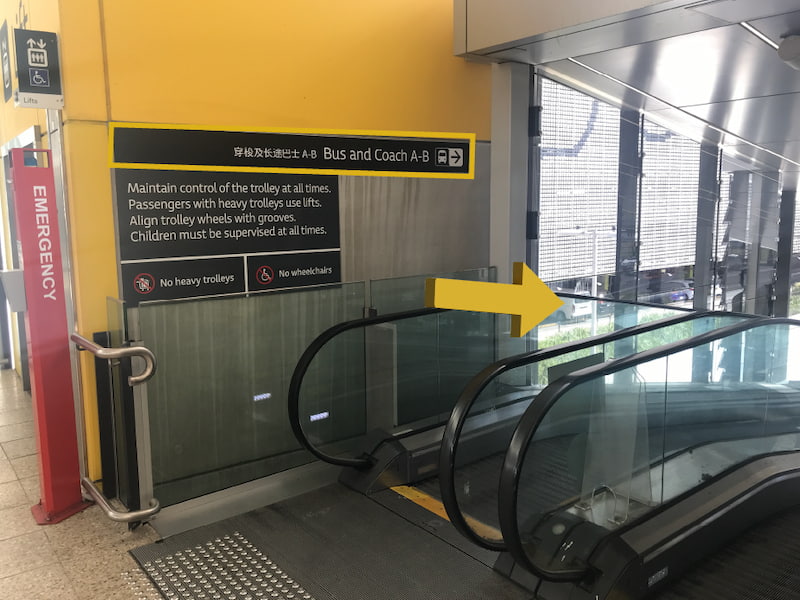 Airport directional sign indicating to turn right - following the escalator down to ground floor