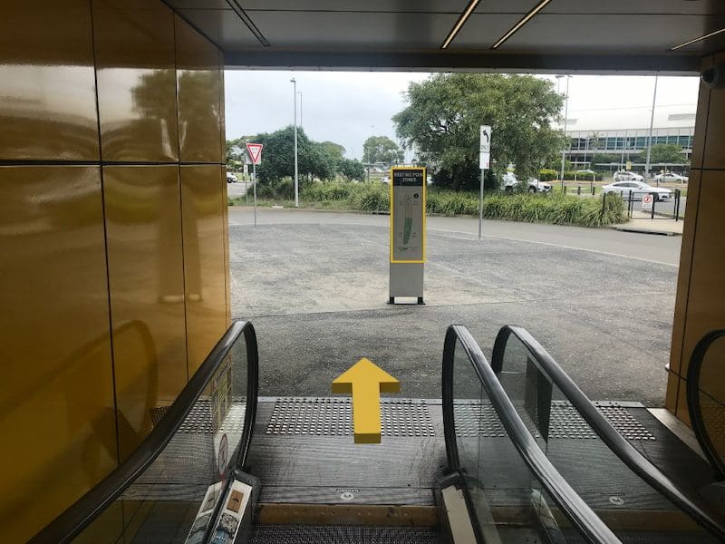 Escalator reaching ground level at airport.