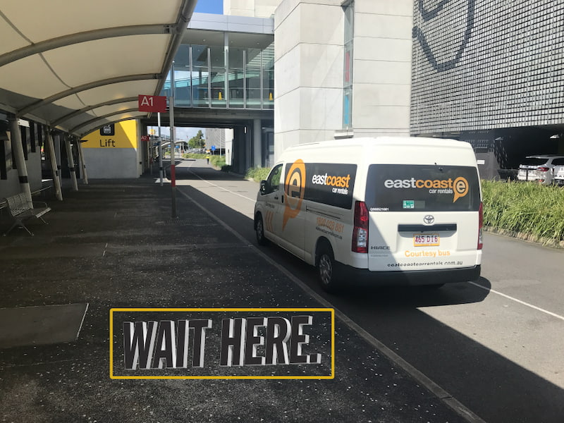 White East Coast Car Rentals shuttle outside of airport parking lot.